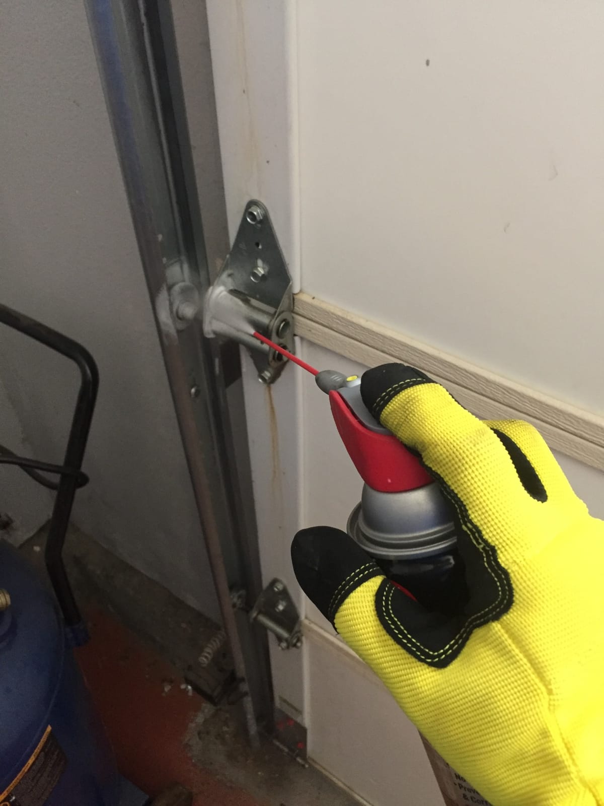 Garage door hardware being adjusted and lubricated