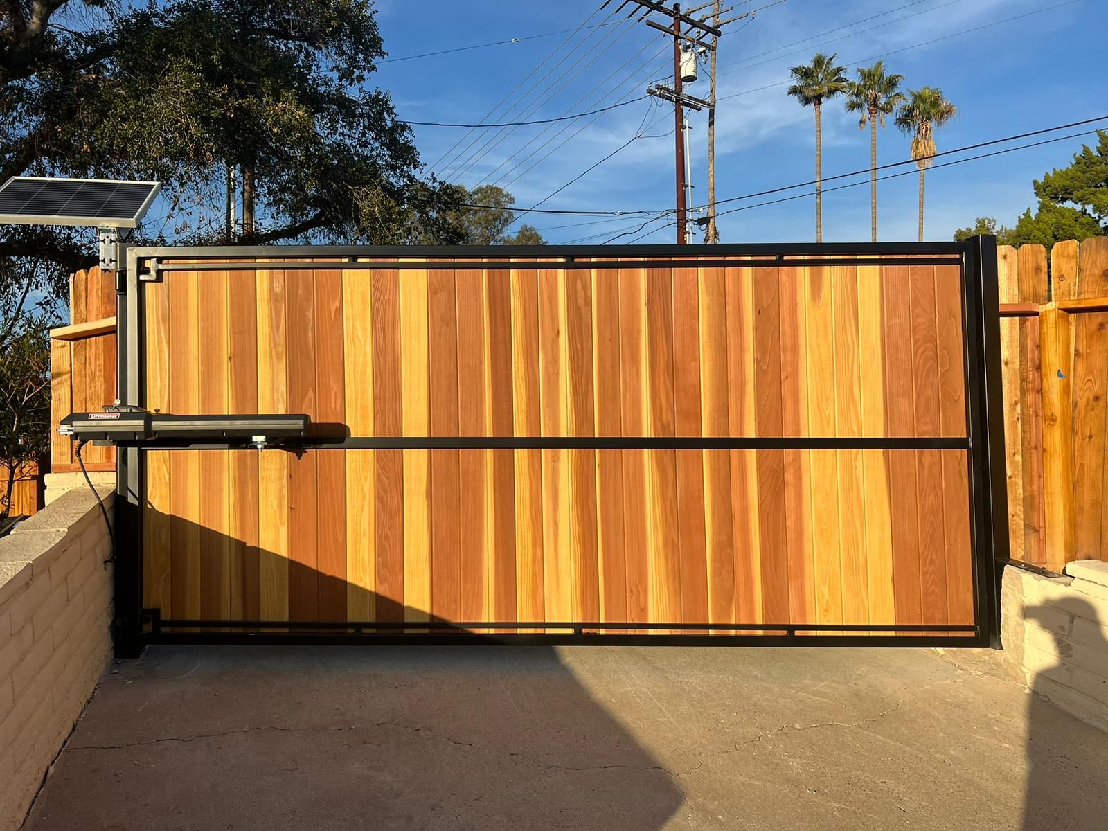 Redwood and steel driveway gate with a solar gate opener